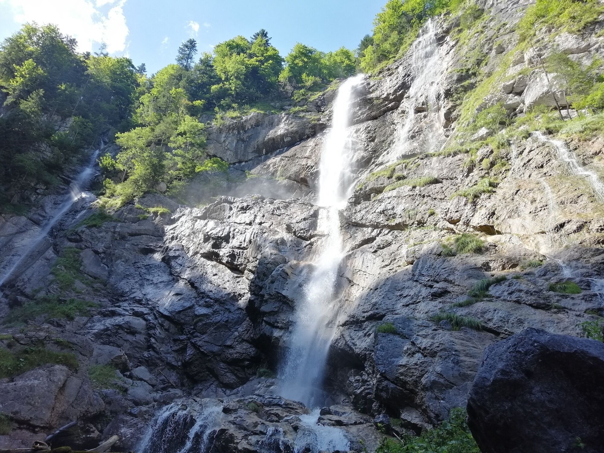 Una cascada se precipita por un risco rocoso rodeado de vegetación.