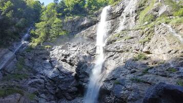 Una cascada se precipita por un risco rocoso rodeado de vegetación.