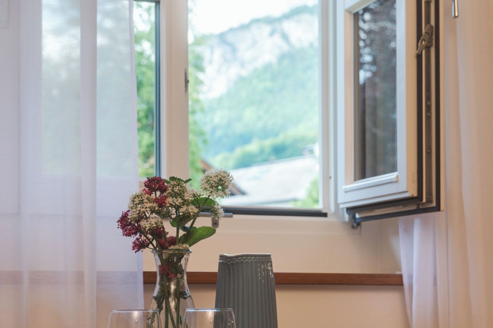 Une pièce avec une grande fenêtre, un vase rempli de fleurs et un radiateur.