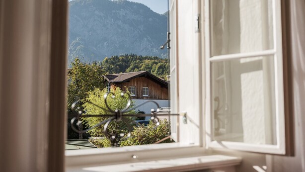 Una ventana con vista a una montaña y un edificio de madera.
