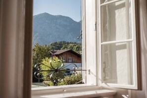 A window with a view of a mountain and a wooden building. - Wanderlust Boutique Rooms (Bad Goisern)