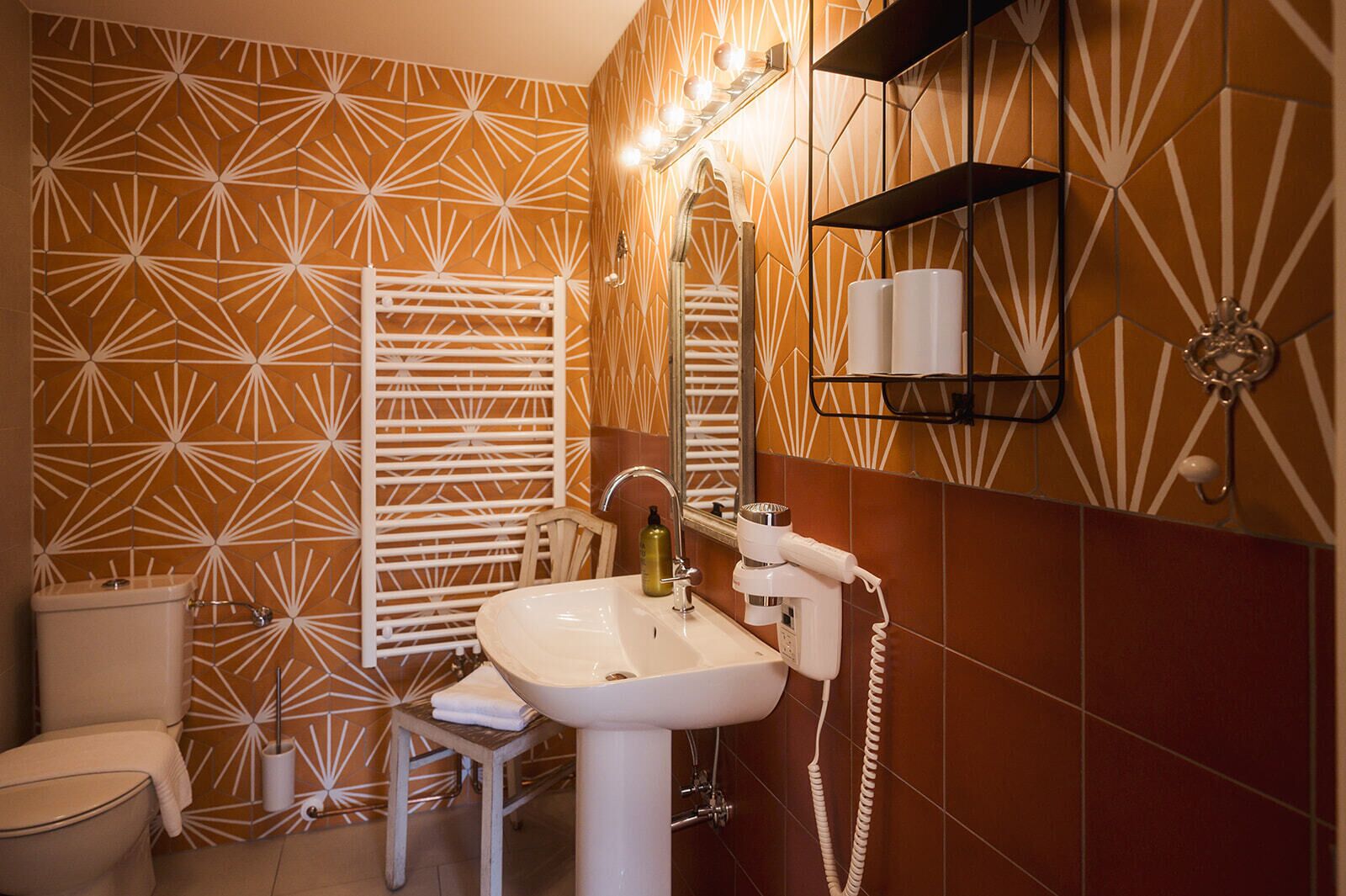 A bathroom with a geometric patterned wall, a white sink, a mirror, and a towel rack.