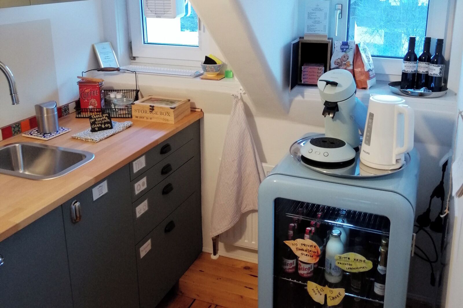 Una cocina compacta con un lavamanos, una cafetera, un refrigerador pequeño y una ventana con vistas.