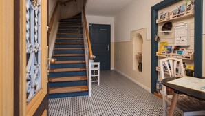 Un pasillo con una escalera, una puerta que indica 'PRIVATE', una estantería con folletos de viajes y una mesa con un mapa.