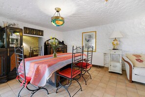 Un comedor con una mesa dispuesta para cuatro, una araña y un sofá blanco con un cojín floral.