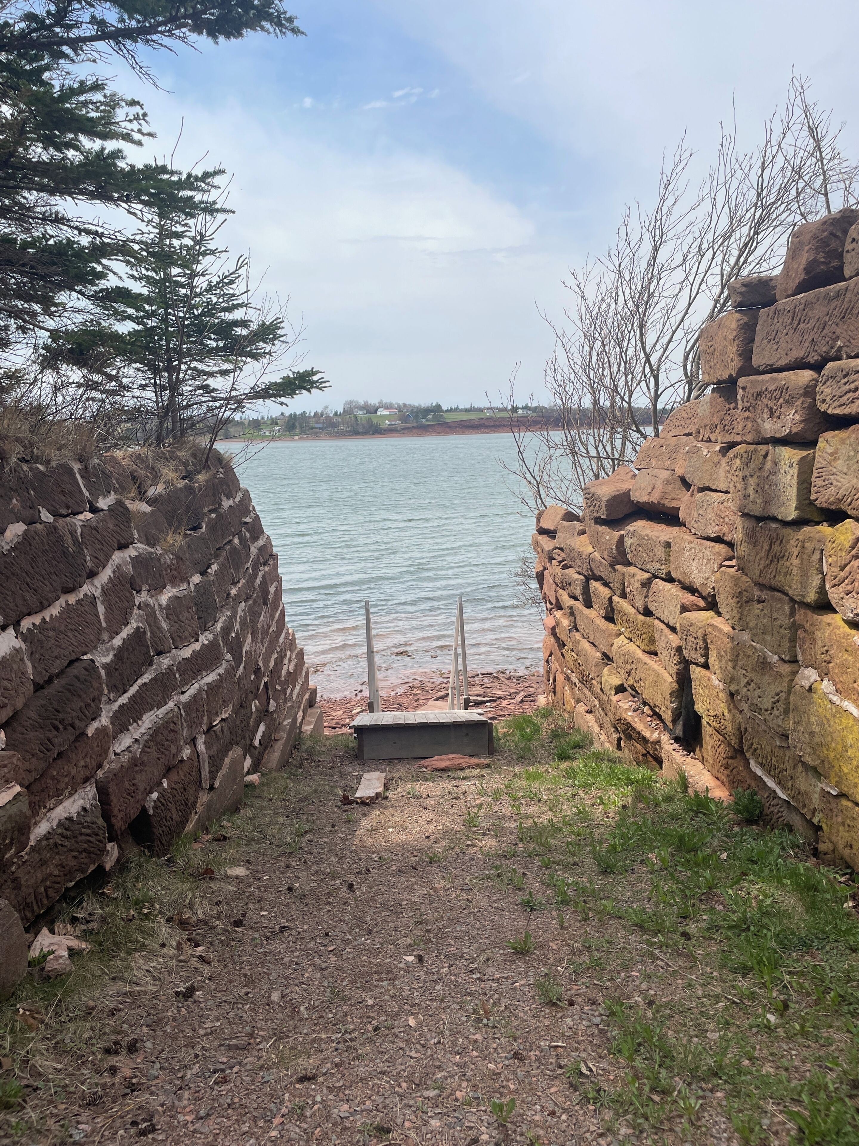 Un mur de pierres qui mène à un plan d’eau, avec un ciel dégagé au-dessus.