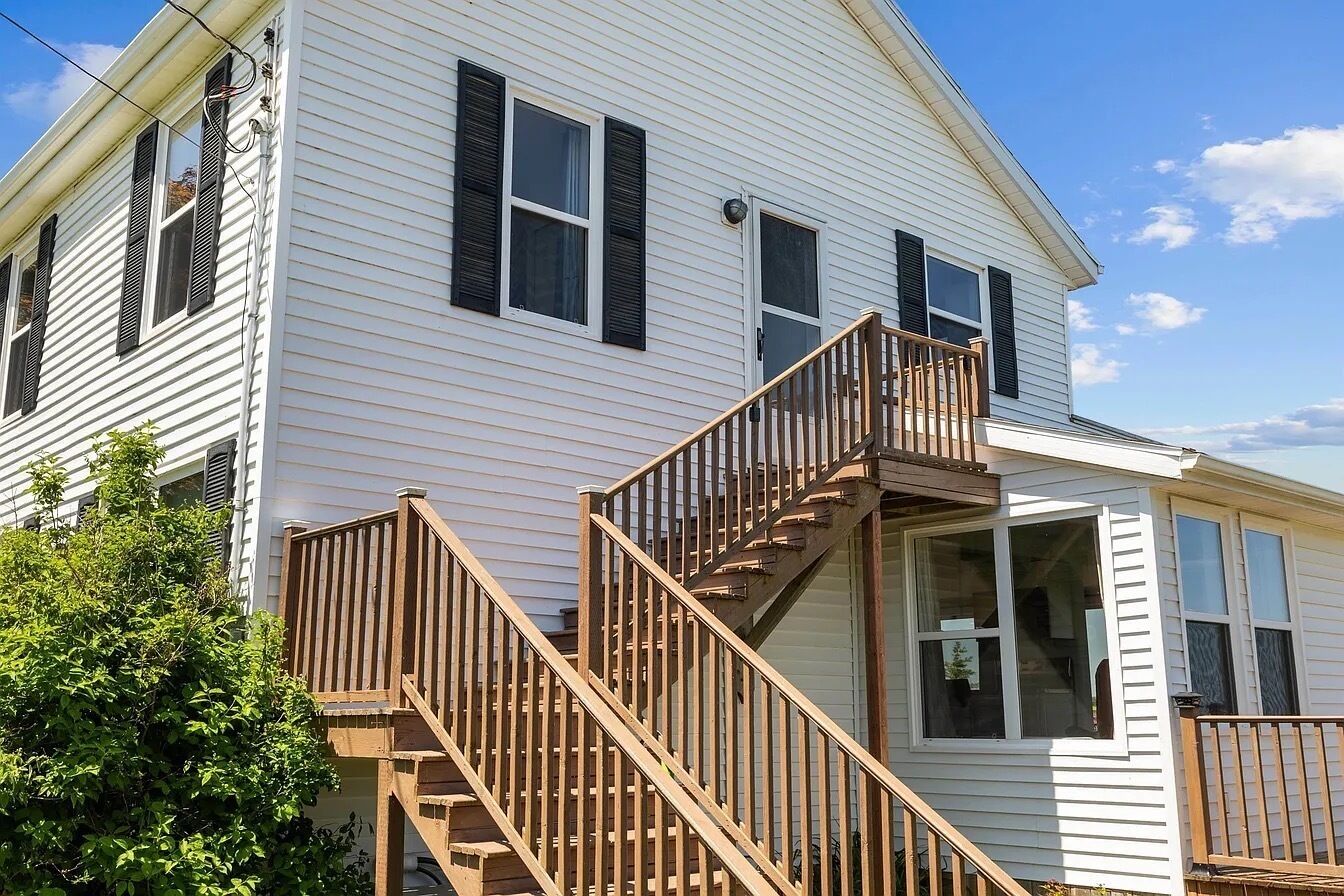 A two-story house with a wooden staircase, a front porch, and a large window.