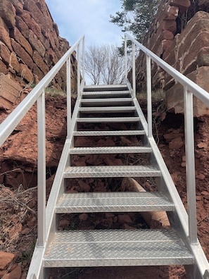 A metal staircase with handrails leading up a rocky terrain.