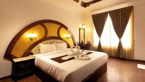 A hotel room with a large bed, a nightstand, a mirror, and a window with curtains. - WELBECK BY THE BEE HIVES (Ooty)