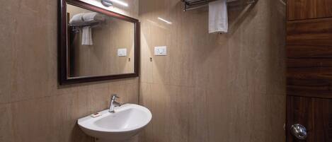 A bathroom with a sink, mirror, towel rack, and wooden door.