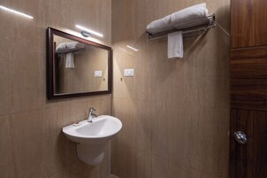Een badkamer met een wastafel, spiegel, handdoekhouder en een houten deur.