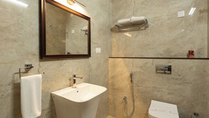 A bathroom with a large sink, a mirror, a towel rack, a shower, and a toilet. - WELBECK BY THE BEE HIVES (Ooty)