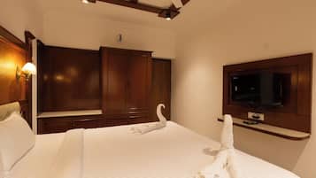 Ein Hotelzimmer mit einem großen Bett, einem Holzschrank, einem Flachbildfernseher und einem Deckenventilator.