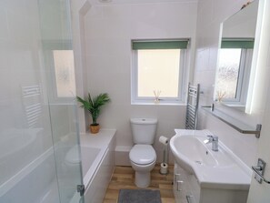 Une salle de bain avec une douche à parois de verre, des toilettes, une baignoire, un lavabo et une fenêtre donnant sur un beau paysage.