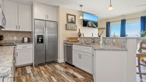Una cocina moderna con armarios blancos, electrodomésticos de acero inoxidable, una encimera de granito y una isla grande.