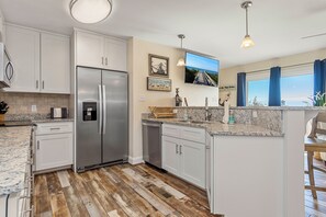 A modern kitchen with white cabinets, stainless steel appliances, a granite countertop, and a large island. - Knot on Call a 4BR Coastal Retreat w/ Pool Hot Tub & Ocean Views – Walk to Beach (Emerald Isle)