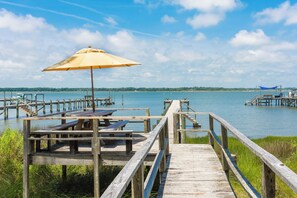 Une jetée en bois, agrémentée de tables de pique-nique et d’un parasol, qui mène à une étendue d’eau calme.