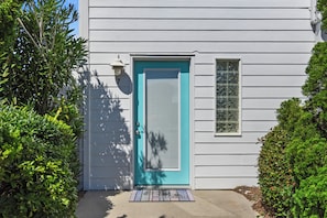 Une maison avec une porte bleue, une petite fenêtre et un paillasson.