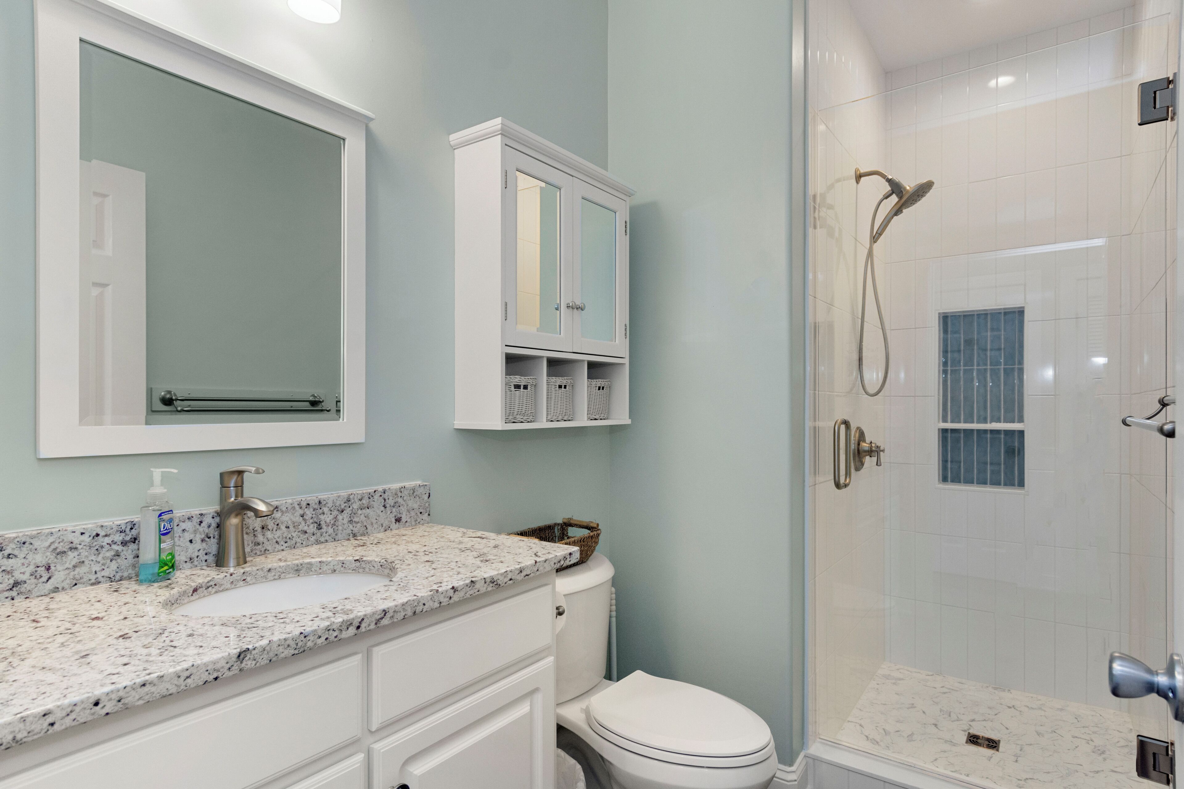 A bathroom with a sink, mirror, cabinet, toilet, and shower.