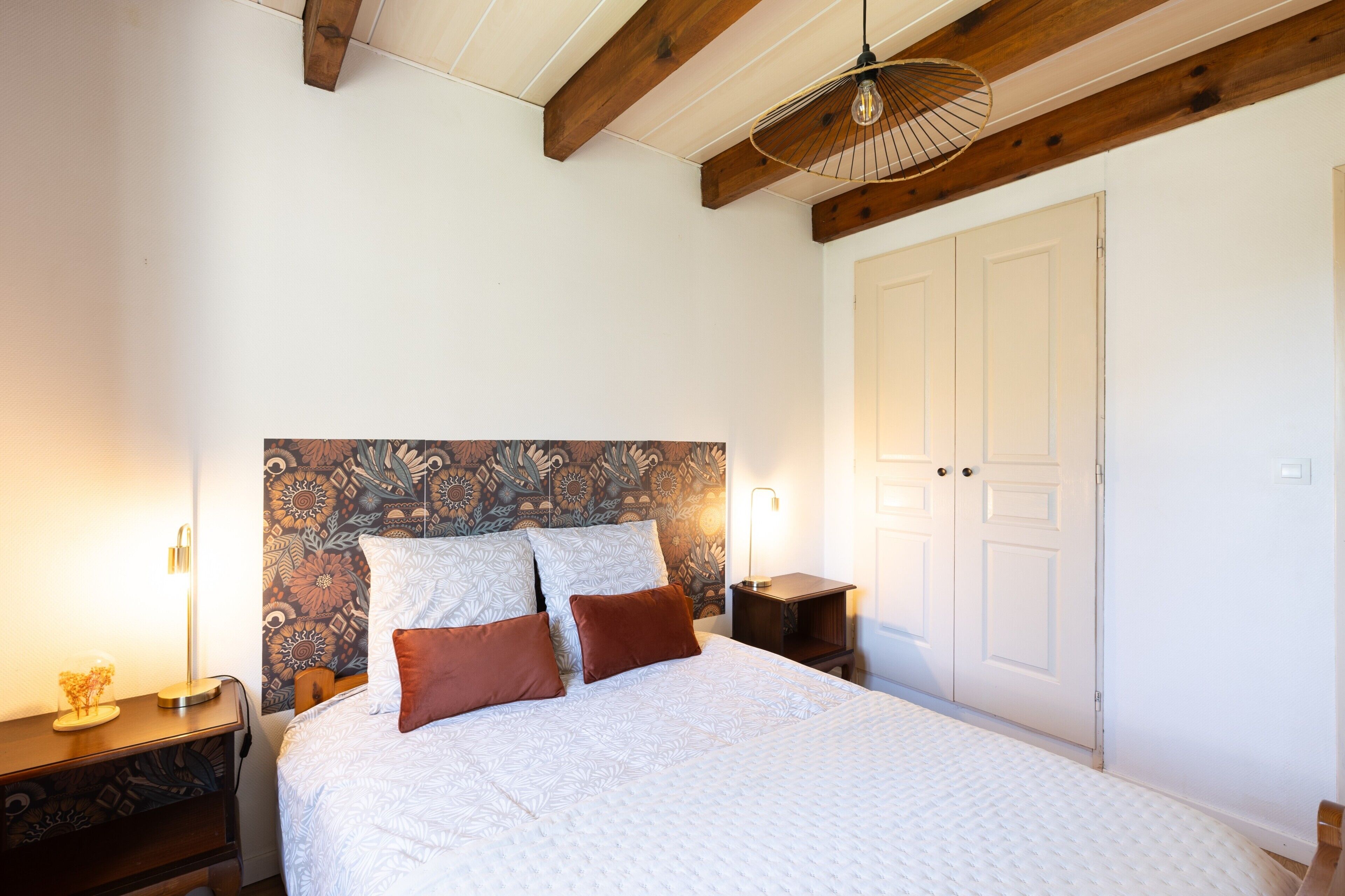 A bedroom with a bed, wooden headboard, bedside tables, and a wardrobe.