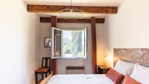 Une chambre à coucher avec un lit, une fenêtre, une chaise et une table de chevet.