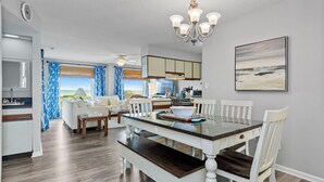 Uma cozinha moderna com área de refeições, vista para o oceano e um lustre.