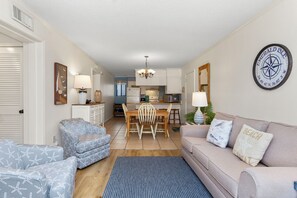 Ein Wohnzimmer mit Sofa, Sessel und Esstisch mit Stühlen.