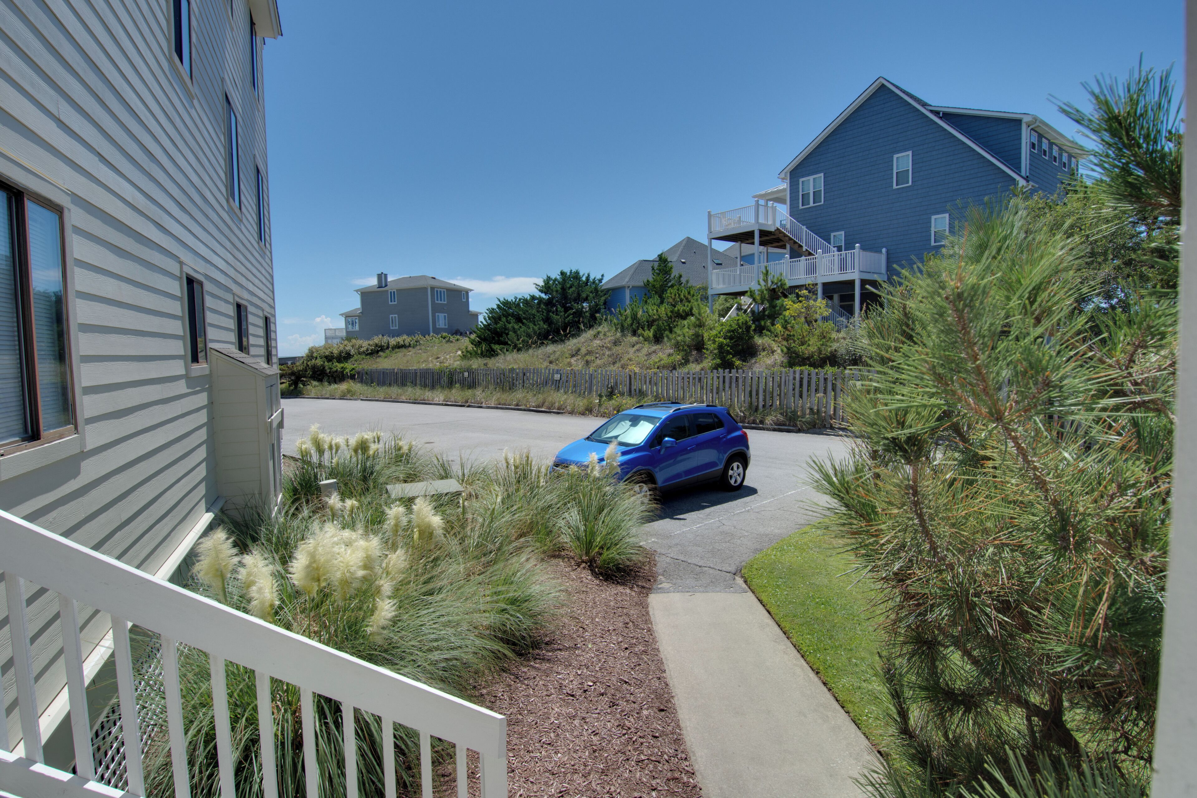 A residential area with houses, a car, and a sidewalk.