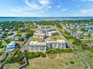 Un quartier résidentiel en bord de mer, avec des immeubles d’appartements modernes, un parking et une plage en arrière-plan.