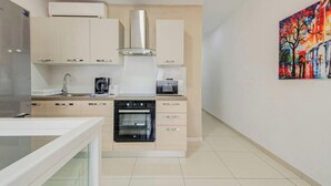 A modern kitchen with a built-in oven, a coffee maker, and a microwave. - Msida 2BR Home Near University w/ Terrace & WiFi (Msida)