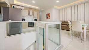 A modern kitchen with a dining area, white cabinetry, and a glass partition. - Msida 2BR Home Near University w/ Terrace & WiFi (Msida)