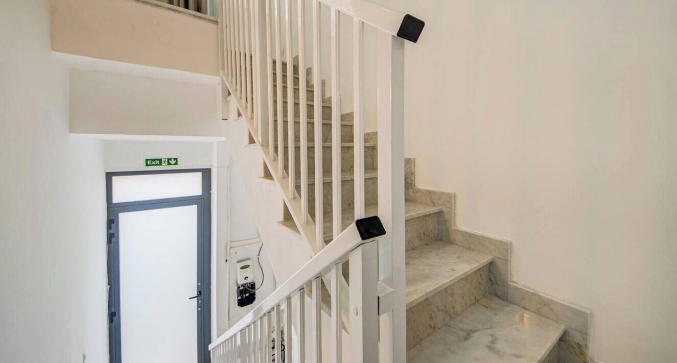 Una escalera con barandillas blancas y escalones de mármol.
