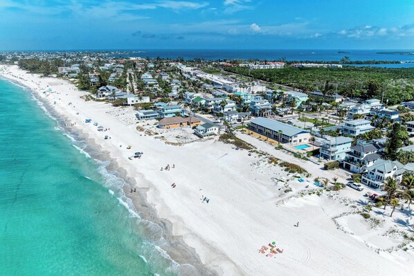 A coastal resort with beachfront properties, a sandy beach, and a clear view of the ocean.