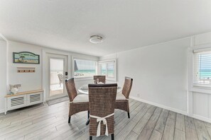 A dining area with wicker chairs, a round table, and a bench.