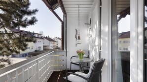 Ein Balkon mit Tisch und Stühlen, einer H ängelampe und Blick auf benachbarte Häuser.