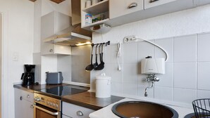 Eine Küche mit Herd, Backofen, Spüle und verschiedenen Kochutensilien.