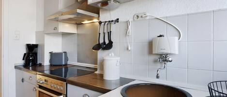 Una cucina completa di piano cottura, forno, lavello e diversi utensili.