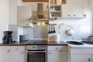 A kitchen with a stove, oven, and a coffee maker.