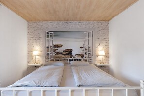 A bedroom with a white brick wall, a bed with two pillows, and two bedside lamps. - Apartment Margot in VS with Balcony and Wi-Fi (Villingen-Schwenningen)