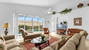 Ein Wohnzimmer mit einem Glastisch, zwei Sofas, einem Fernseher und einem Deckenventilator.