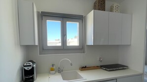 Una cocina moderna con ventana, cafetera, lavamanos y tostadora.