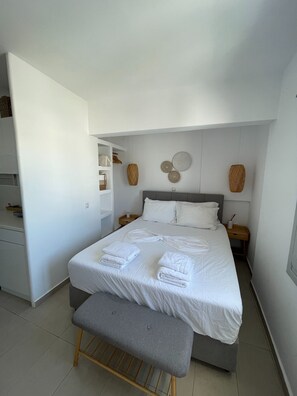 Ein ordentlich eingerichtetes Schlafzimmer mit einem Bett, Nachttischen, einer Bank und einem Kleiderschrank.