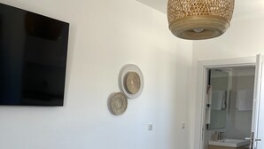 Una habitación moderna con una televisión de pantalla plana, una lámpara colgante tejida y dos platos decorativos colgados en la pared.