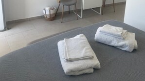Una habitación moderna con una cama, dos sillones, una mesita, un televisor y una lámpara colgante.