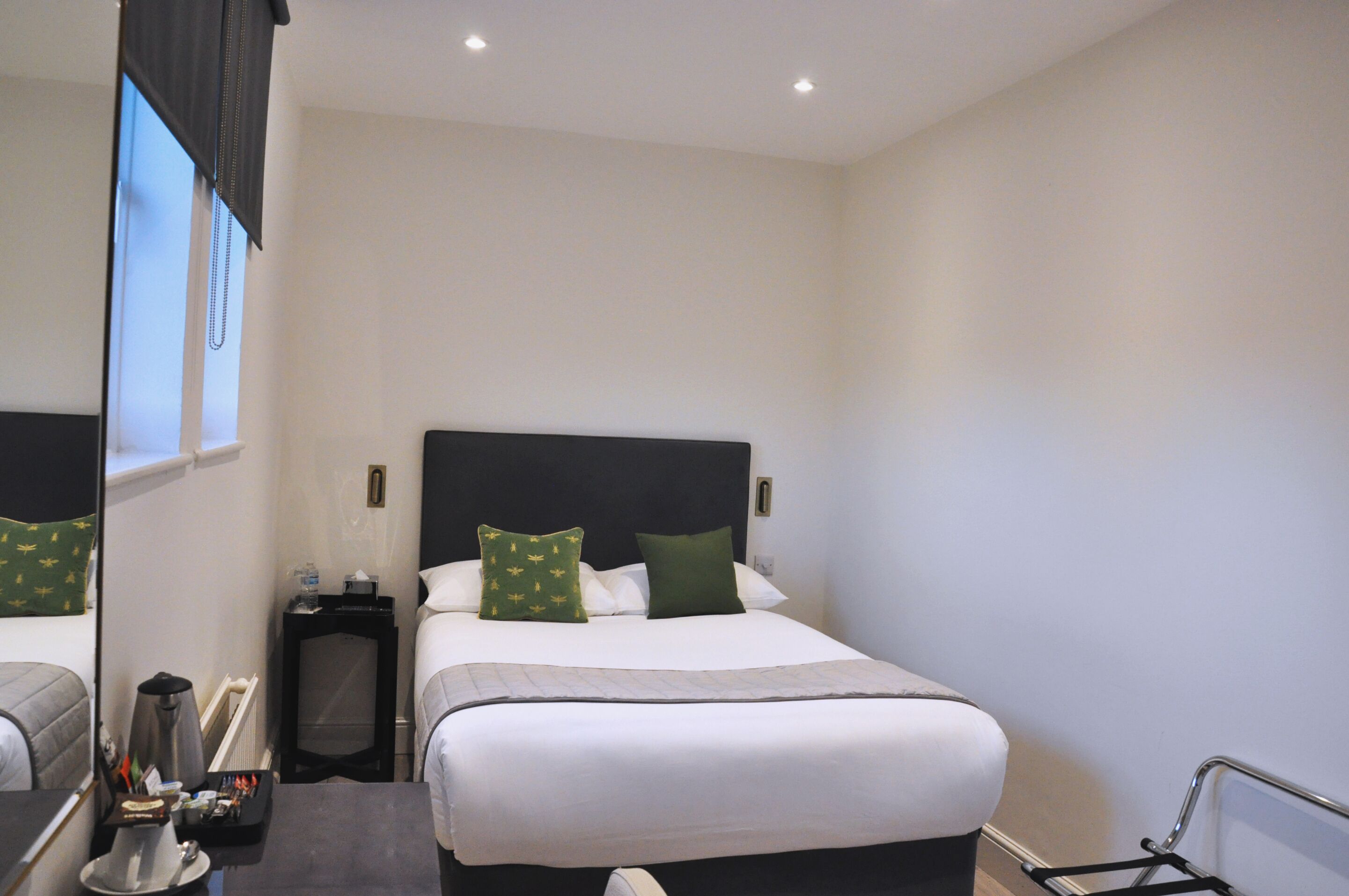Ein Hotelzimmer mit Bett, Nachttischen, einem Sessel und einem Fenster.