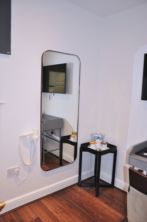 A bathroom with a large mirror, a small table with toiletries, and a cabinet above the mirror. - Nap Barnet Hotel (Barnet)