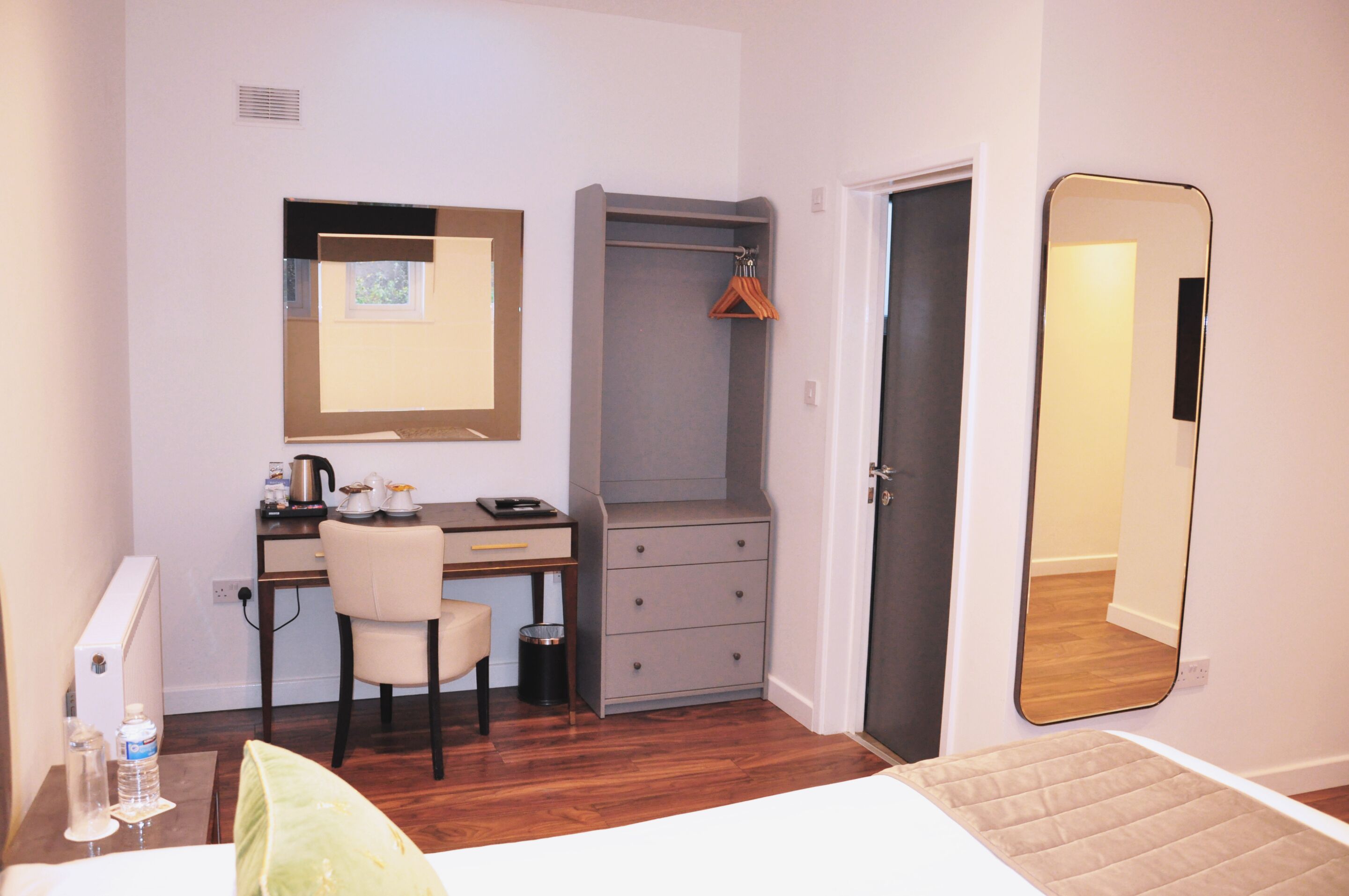 A bedroom with a bed, a desk, a chair, a wardrobe, and a mirror.