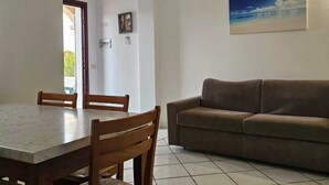 Un comedor con una mesa de mármol y sillas de madera, un sofá marrón y un cuadro en la pared.