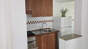 Una cocina compacta con armarios de madera, un fregadero, una estufa y un refrigerador.