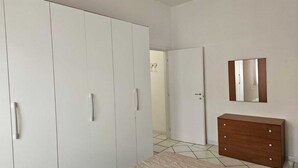 Un dormitorio con armario, cómoda y espejo en la pared.
